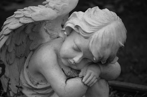 Grayscale Photo of a Baby Angel Sculpture