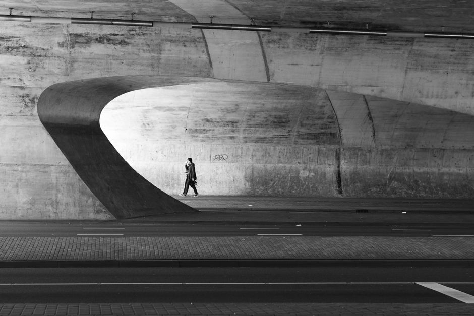 A person walks alone in a modern architectural tunnel, creating a striking urban scene.