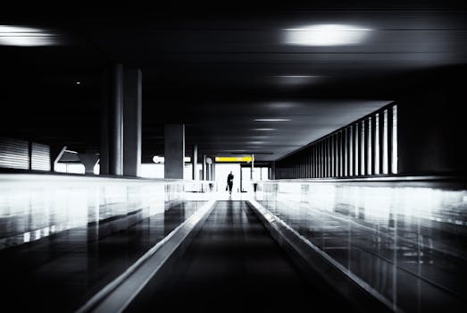 一个身影走过灯光明亮的现代机场黑暗隧道