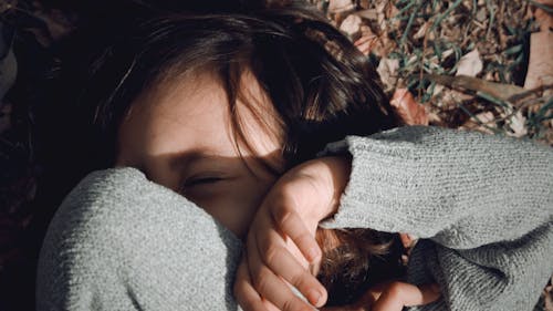 Free A Child Lying on the Ground Covering Face Stock Photo