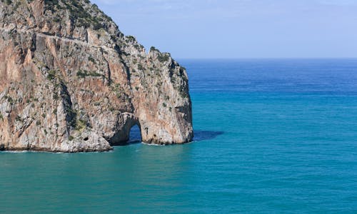 Brown Rock Formation on Blue Sea Under Blue Sky