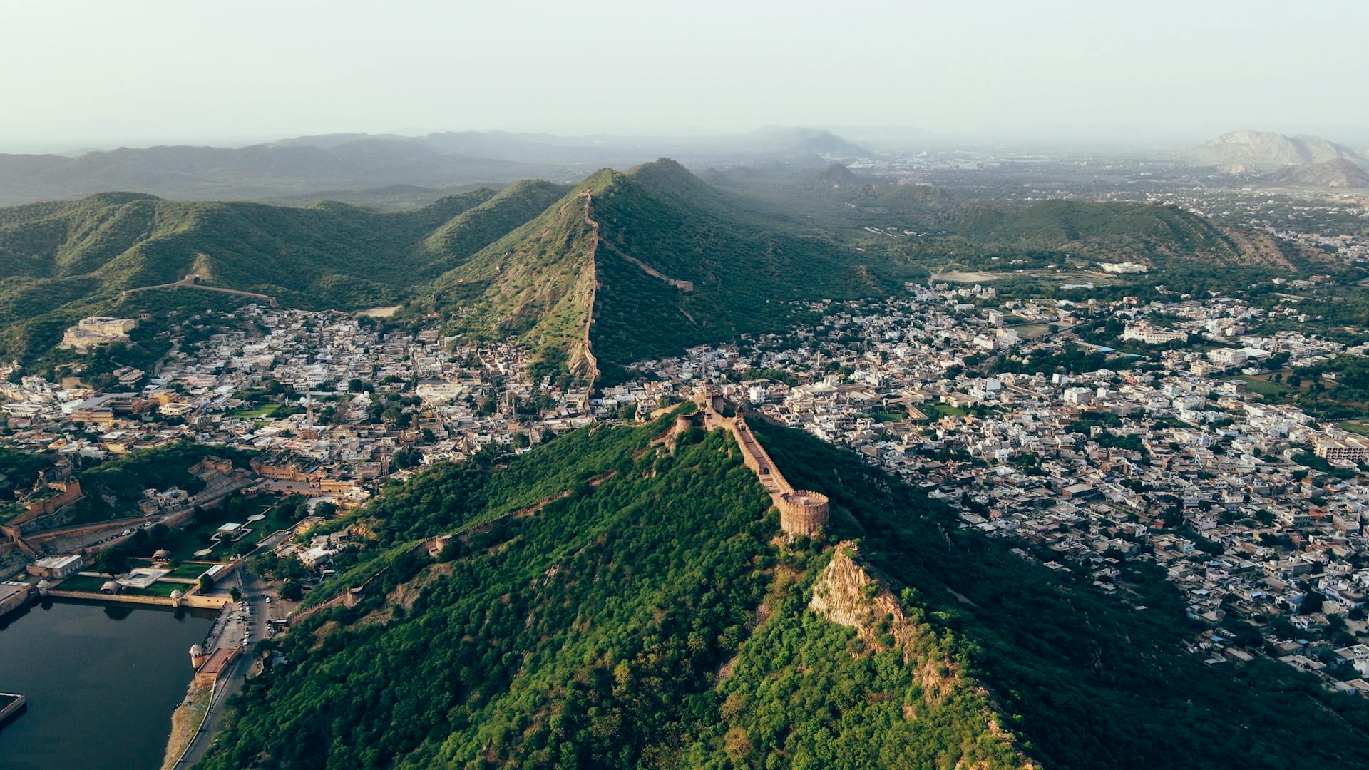 A stunning aerial view of Jaipur city, India, showcasing its historic fortifications and lush mountain ridge.