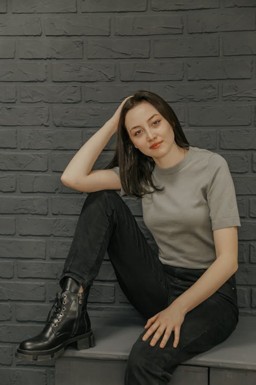 Woman in Gray Shirt and Black Pants Sitting on a Table