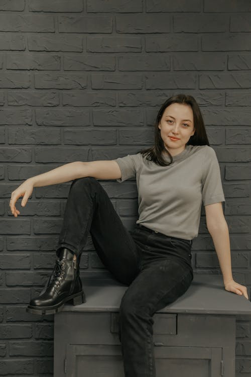 Woman in Gray Shirt and Black Pants Sitting on a Table