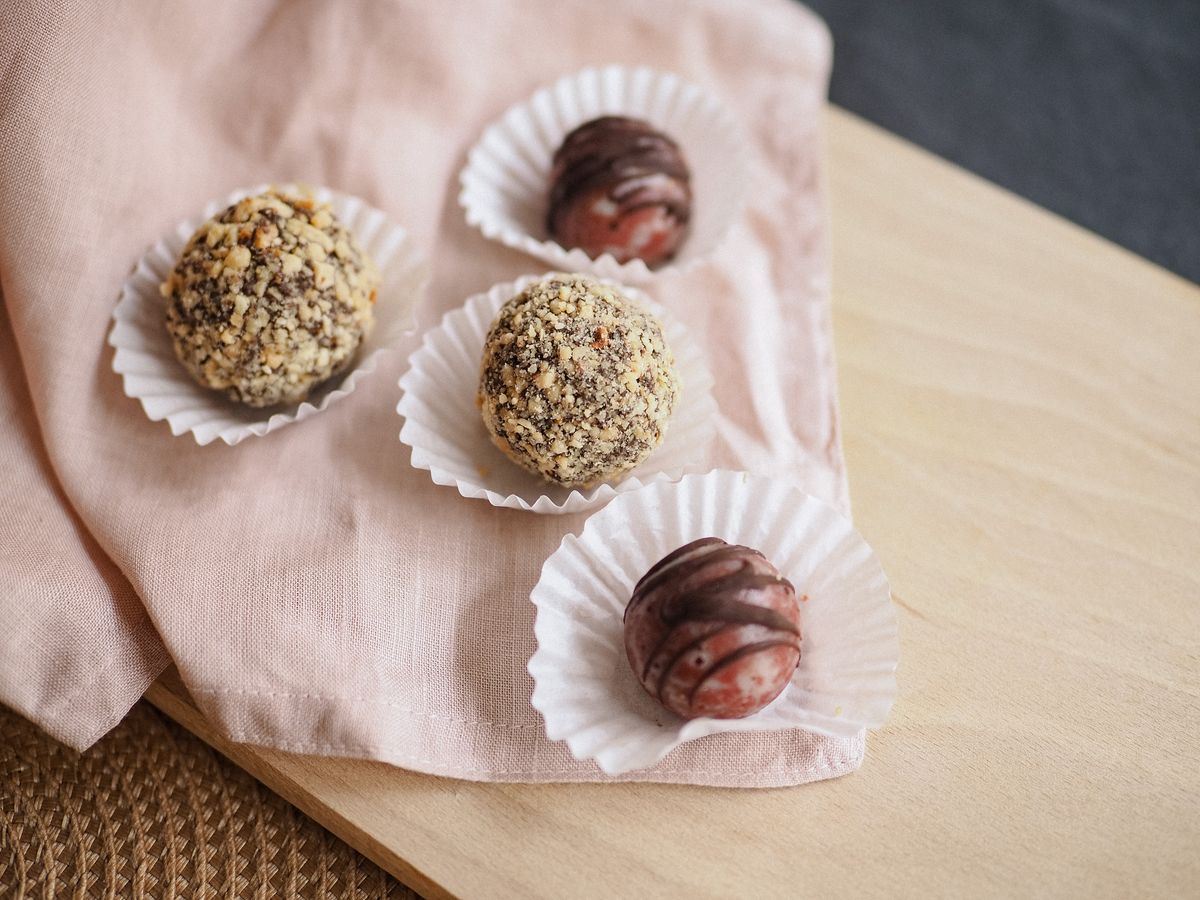 Hand-rolled hazelnut and berry truffles in fluted paper cases on pink linen — photo by Pelageia Zelenina on Pexels