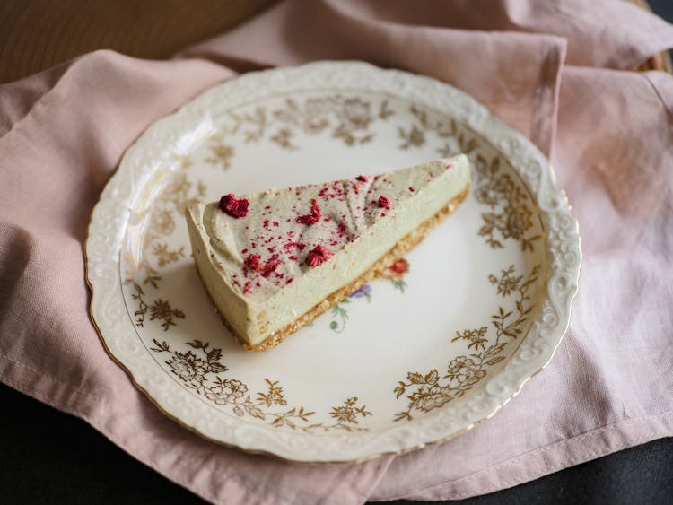 Cheesecake Triangle Sprinkled With Red Castor Sugar Laying On Ornamental Plate