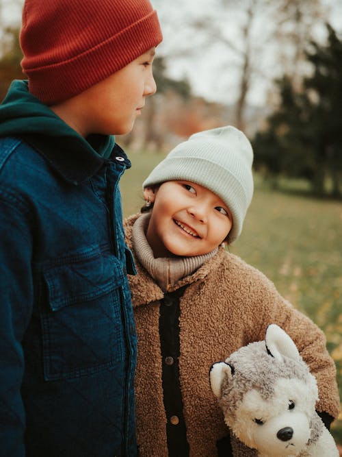Free Boy and Smiling Girl with Toy Dog Under Arm Standing in Park Stock Photo