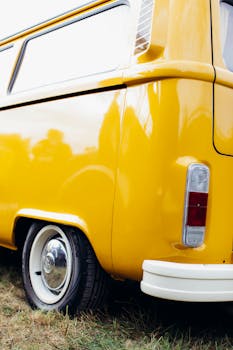 Close-up view of a yellow vintage Volkswagen van with reflections, highlighting retro automotive design.