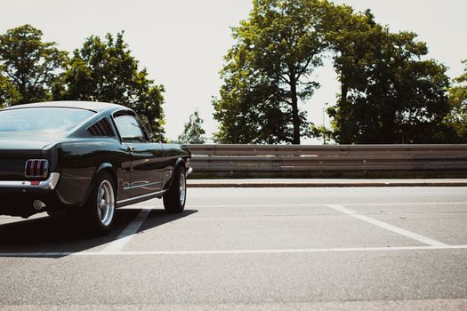 A vintage Ford Mustang parked in an outdoor lot on a sunny day. Iconic classic car with shining exterior.