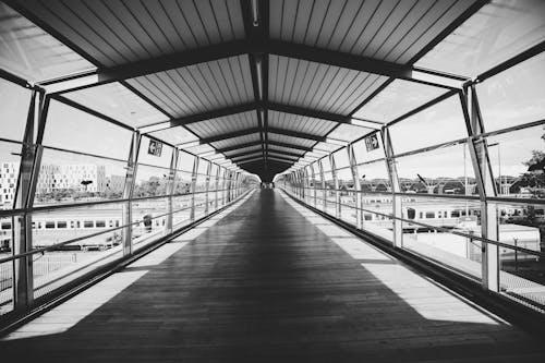 Free Grayscale Photo of a Footbridge at a Train Station Stock Photo