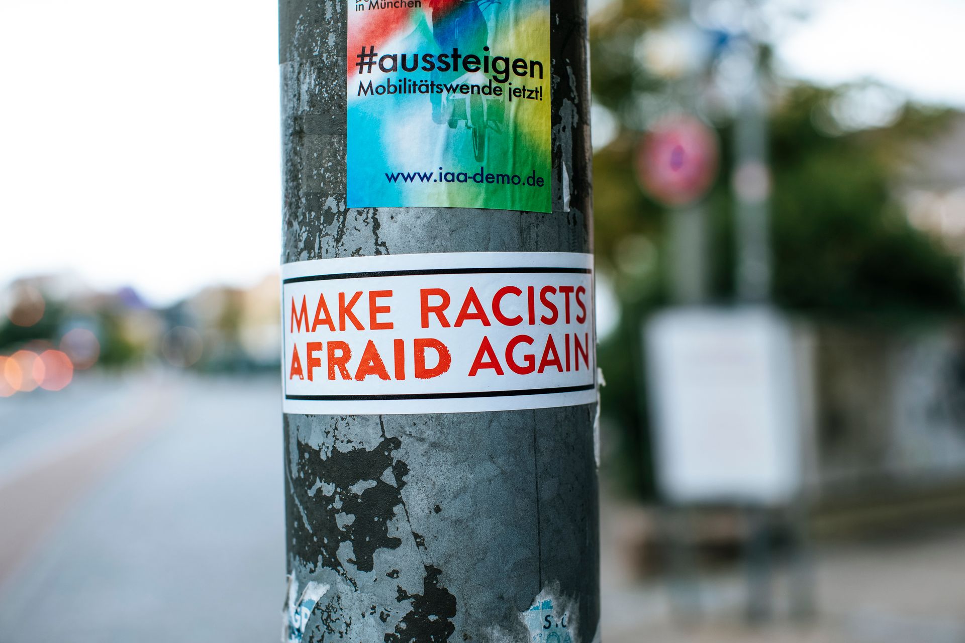 Close-up of a pole with activist stickers, including 'Make Racists Afraid Again.'