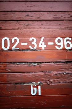 Close-up of a rustic wooden wall featuring white numeric markings on a reddish-brown background.