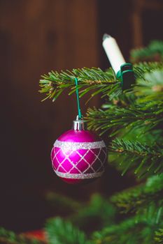 Close-up of a shiny fuchsia bauble ornament on a Christmas tree, adding festive charm indoors.