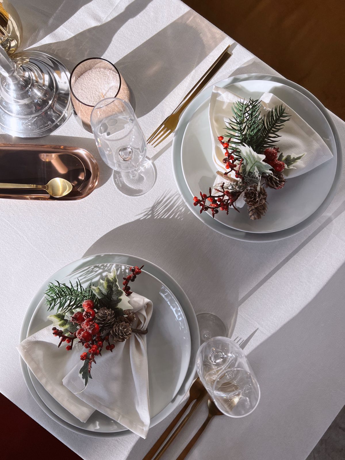 All-white Christmas table setting with white plates and cloth