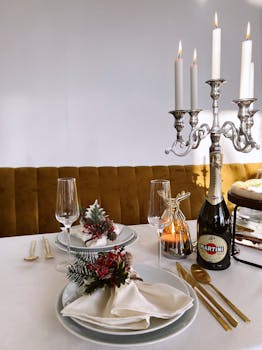 Sophisticated dinner setup featuring candles, gold cutlery, and festive decorations.