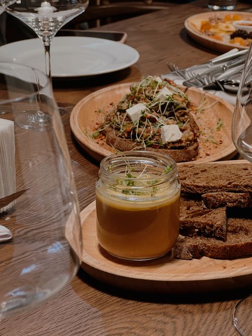 Free Close-up of a meal with bread, jar of soup, and a place setting on a wooden table. Stock Photo