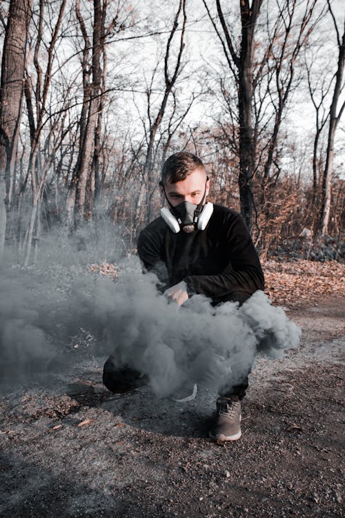 Free A Man Wearing a Gas Mask Crouching on the Ground Stock Photo