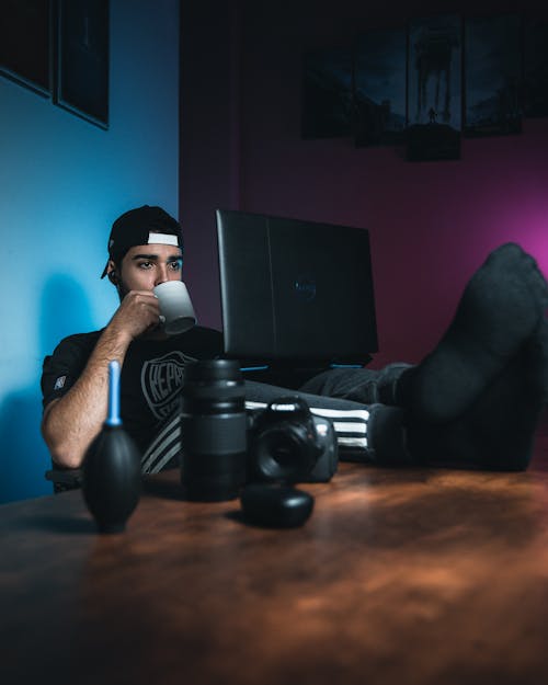 A Man Drinking Beverage while Restin His legs on a Table