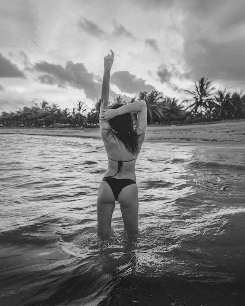 Free Grayscale Photo of a Sexy Woman in Black Bikini Standing in the Water Stock Photo