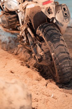 Close-up of a motorcycle wheel navigating through sandy terrain, showcasing off-road adventure.