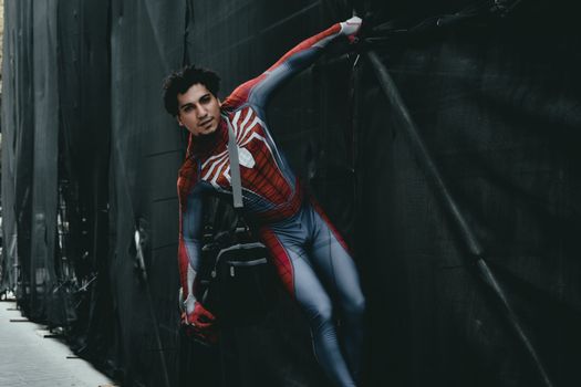 Cosplayer dressed as Spider-Man with a shoulder bag in an urban setting.