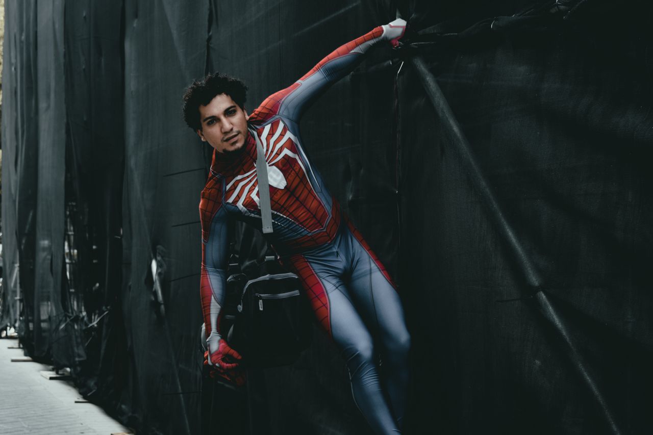 cosplayer dressed as spider man with a shoulder bag in an urban settin