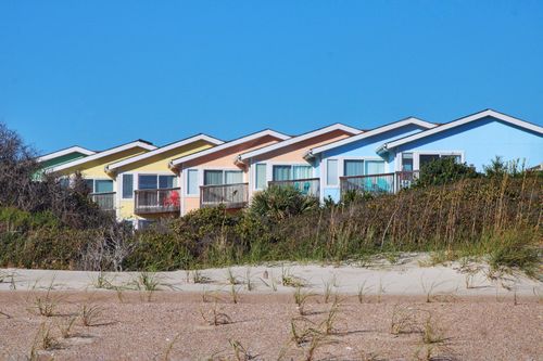 Free Colorful houses line a beachfront under a clear blue sky, showcasing vibrant architecture. Stock Photo