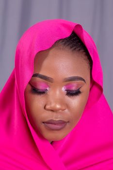 Elegant portrait of a woman in a vibrant pink hijab with closed eyes, showcasing beauty and grace.