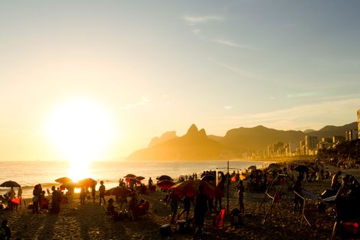 Scenic sunset at Ipanema Beach, Rio de Janeiro, with crowds and vibrant atmosphere.