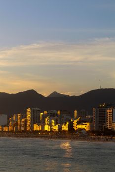 Captivating sunset view of a cityscape with mountains and sea, reflecting warm hues.