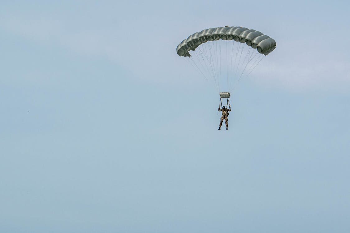 Person in Black Jacket and Black Pants With Blue Parachute in the Sky