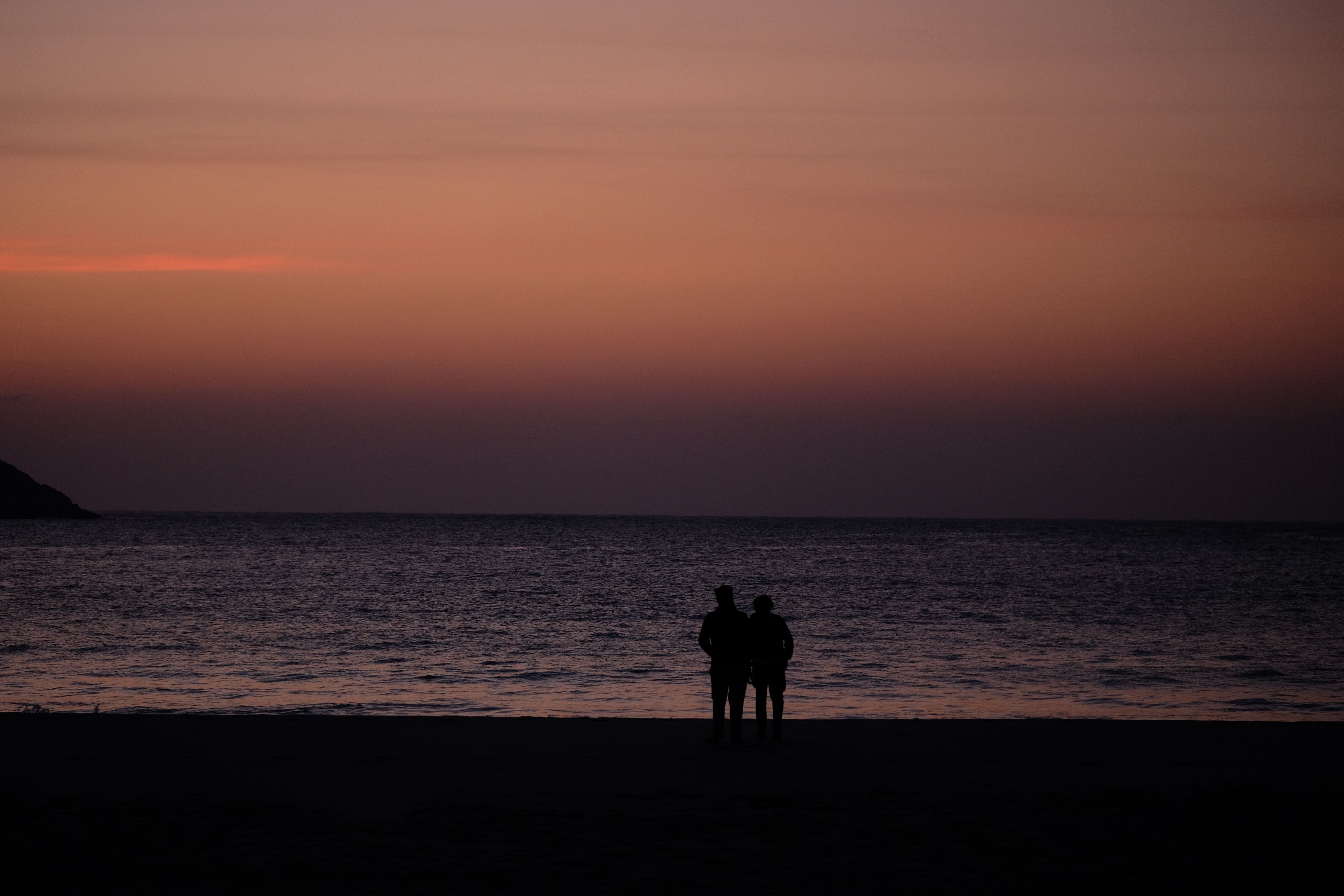 Silhouette of Two People Standing on Beach during Sunset · Free Stock Photo