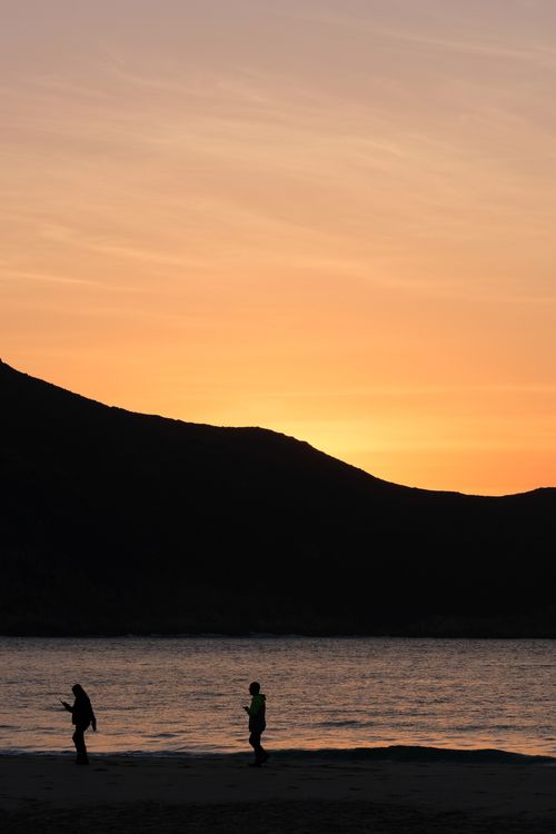 Free Silhouetted figures on a beach with a breathtaking sunset backdrop, capturing the serene evening vibe. Stock Photo
