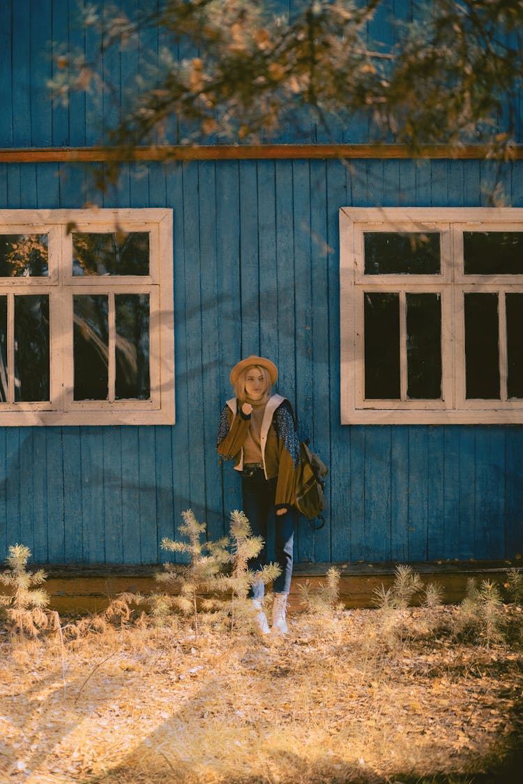 A Woman Leaning On A Blue Wooden House