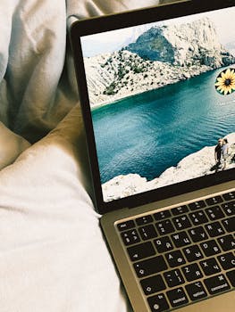 Close-up of a MacBook on a bed, displaying a stunning scenic background.