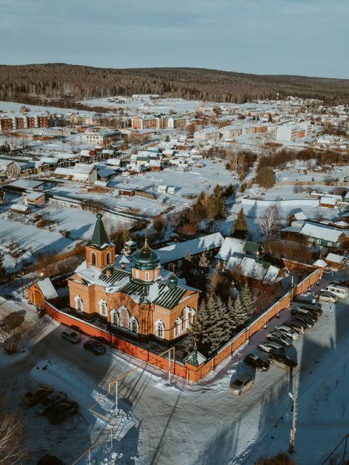 Free Capture of a snowy village with a church and surrounding landscape from above. Stock Photo