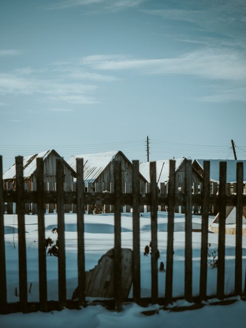 Free Charming wooden fences in a snow-covered rural setting under a clear winter sky. Stock Photo