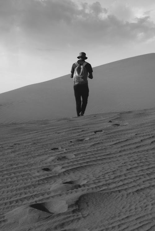 Free Grayscale Photo of a Person Walking in the Desert Stock Photo