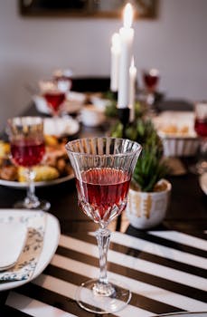 A beautifully set dining table with a focus on a crystal wineglass, creating a warm and inviting atmosphere.