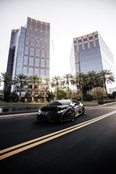 Sleek black Lamborghini sports car driving through an urban street with tall buildings and palm trees.