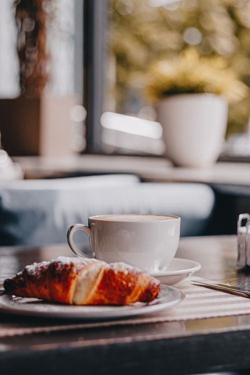 Free Warm and inviting café setting with a cup of coffee and a fresh croissant. Stock Photo