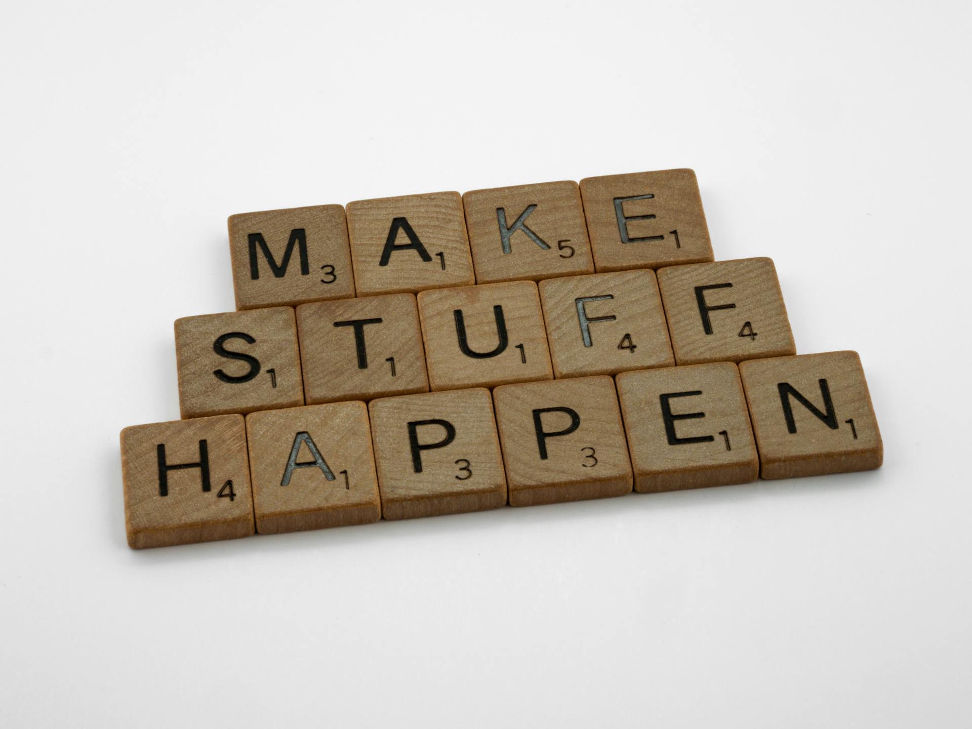 Motivational quote 'Make Stuff Happen' created with scrabble tiles on a clean white background.