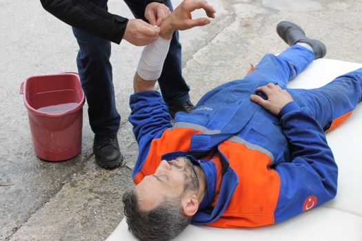 Injured Man lying on the Ground receving a First Aid Treatment 