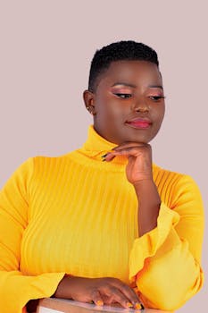 Portrait of an African woman posing in a vibrant yellow turtleneck.
