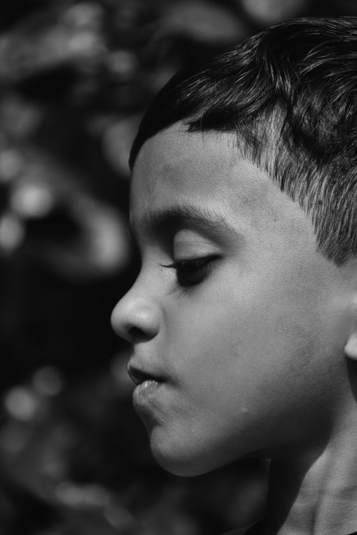 Free Close-up black and white portrait of a boy in profile with a contemplative expression. Stock Photo