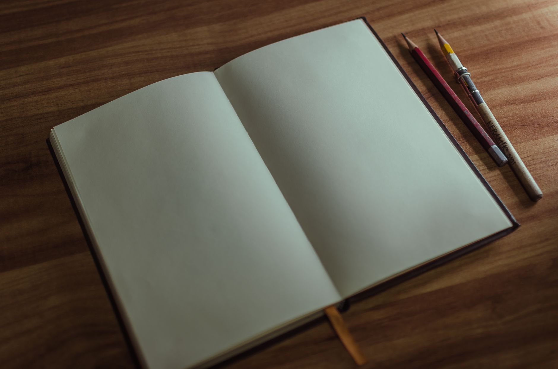 An open sketchbook with pencils on a wooden desk, perfect for artists and creatives.