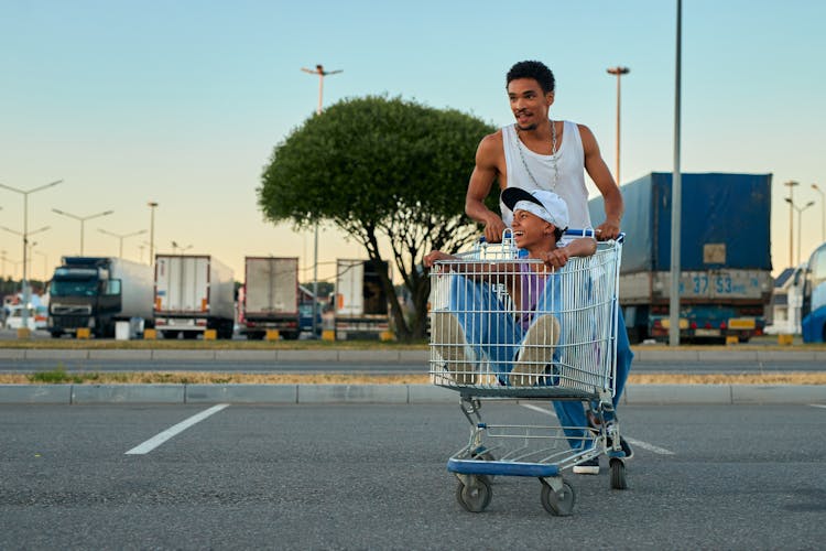 A Man Pushing A Shopping Cart With A Boy