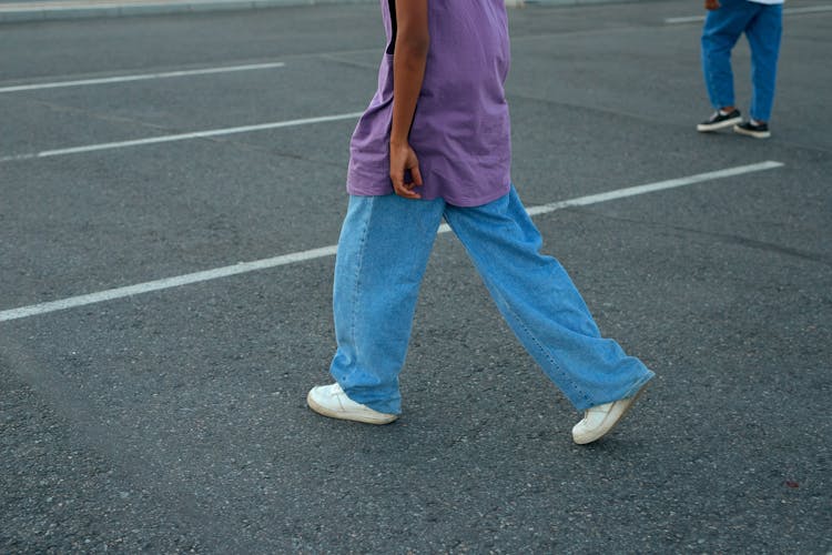 A Person Walking In A Parking Lot