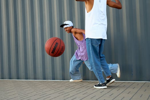 Energetic teens enjoying street basketball in casual attire against an urban backdrop.