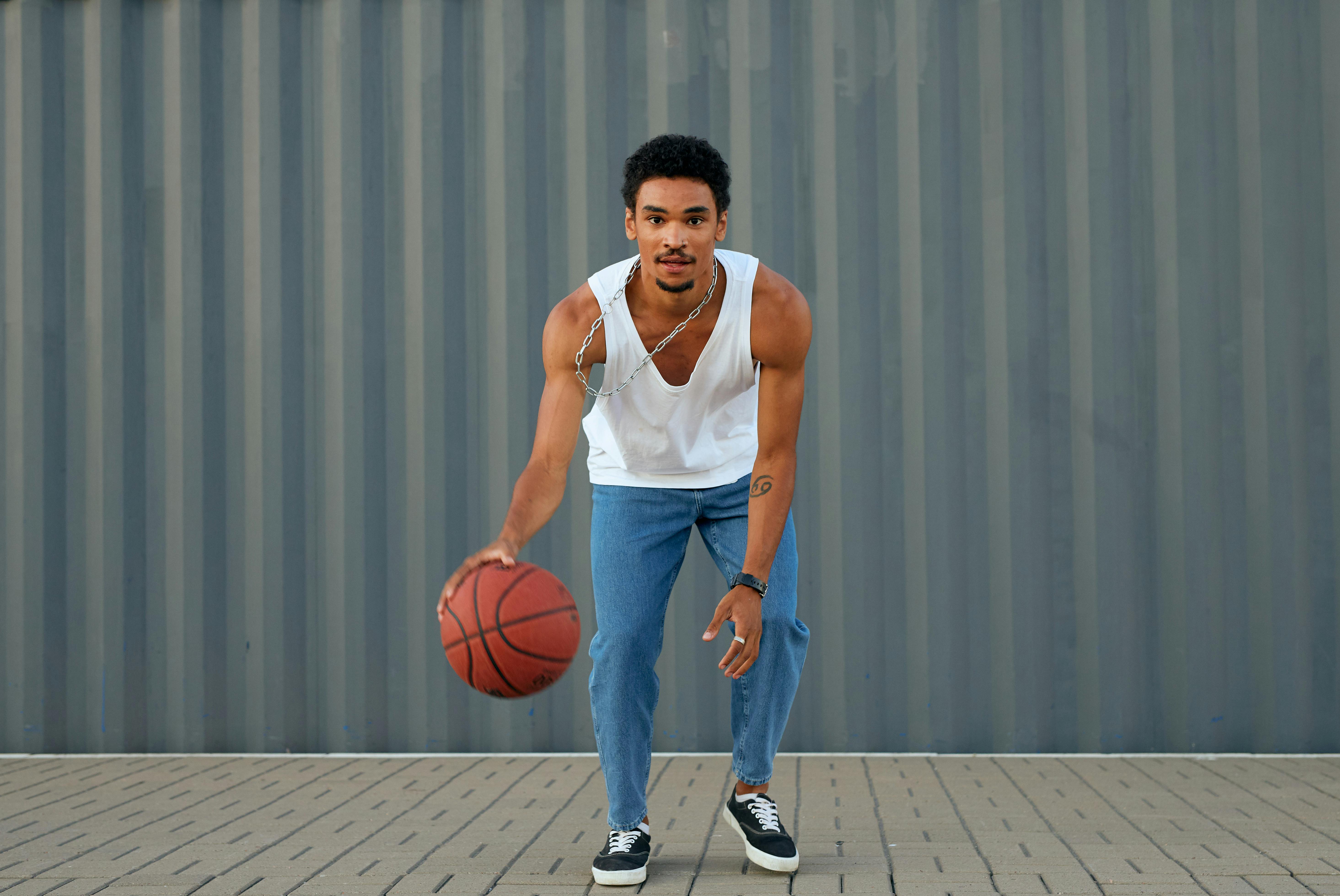 a man in white tank top while dribbling a ball